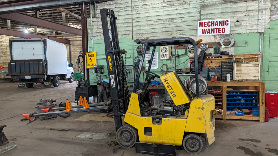 Yellow forklift beside the workbench inside the Dairyland Forklifts shop
