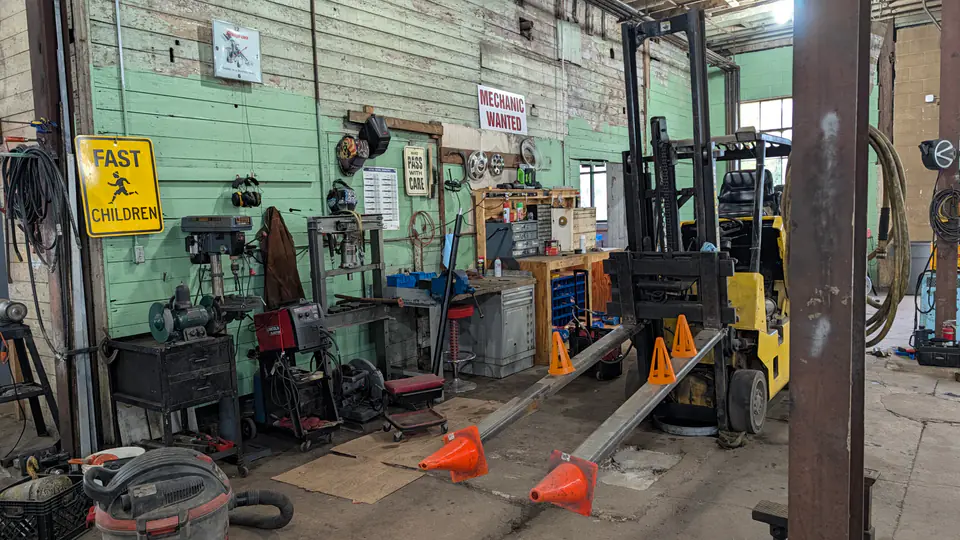 Forklift parked alongside tools and a workbench in the service bay
