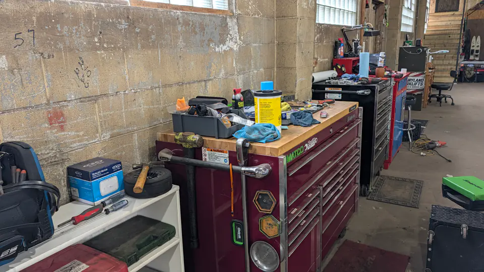 Workshop tools arranged along a bench above red tool drawers